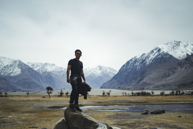 Young indian tourist posing on the high mountain rock in ladakh