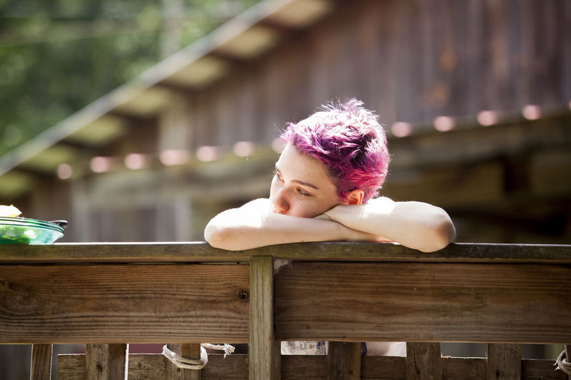Close-up of thoughtful woman leaning on wooden railing
