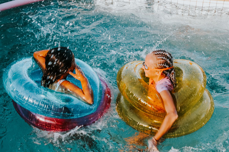 Portrait of girls with inflatable rings swimming in pool