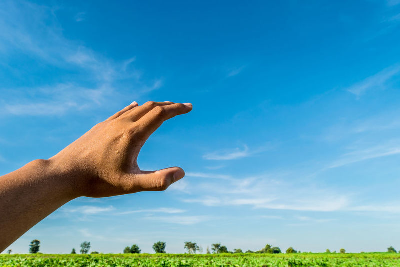 Low angle view of man hand against blue sky