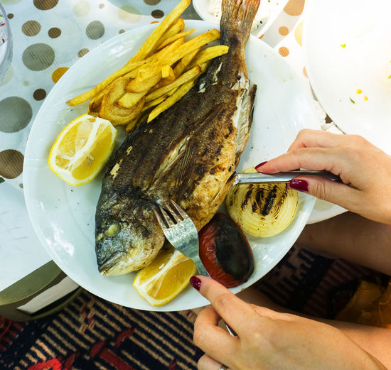 Cropped hands of woman having fish in restaurant