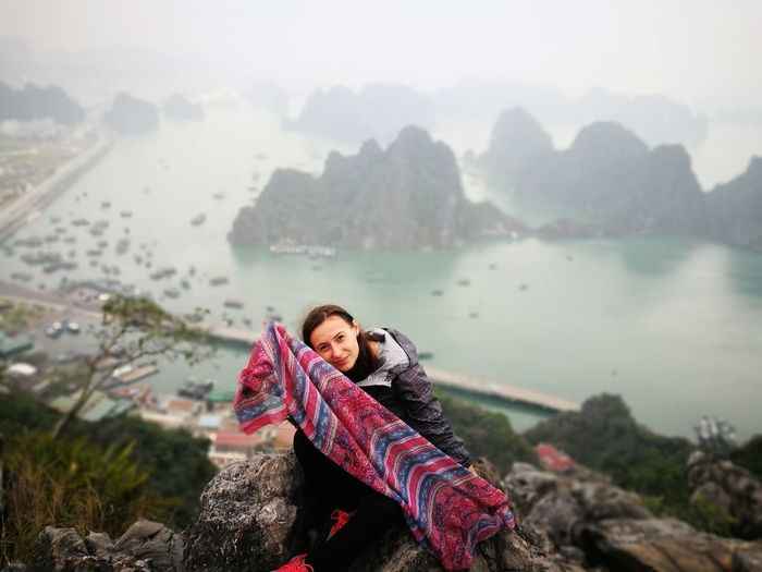 Portrait of woman with scarf sitting on rock