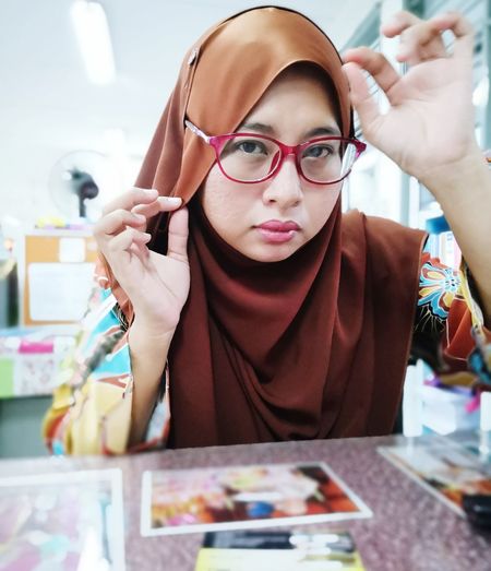 Portrait of woman wearing hijab and eyeglasses at home