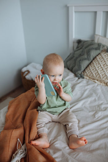 A small child plays on the bed in the phone