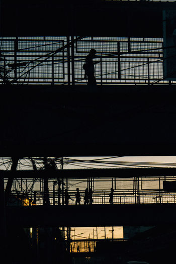 Silhouette man on bridge in city against sky