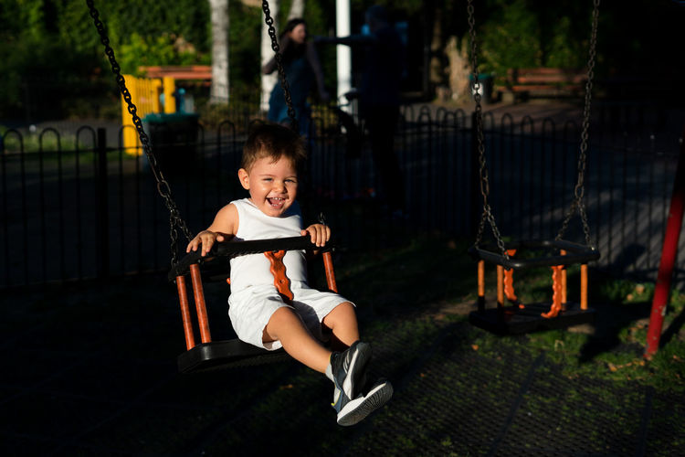 Portrait of smiling girl swinging in playground