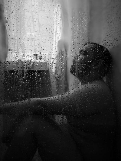 Naked mid adult man taking bath seen through window in bathroom