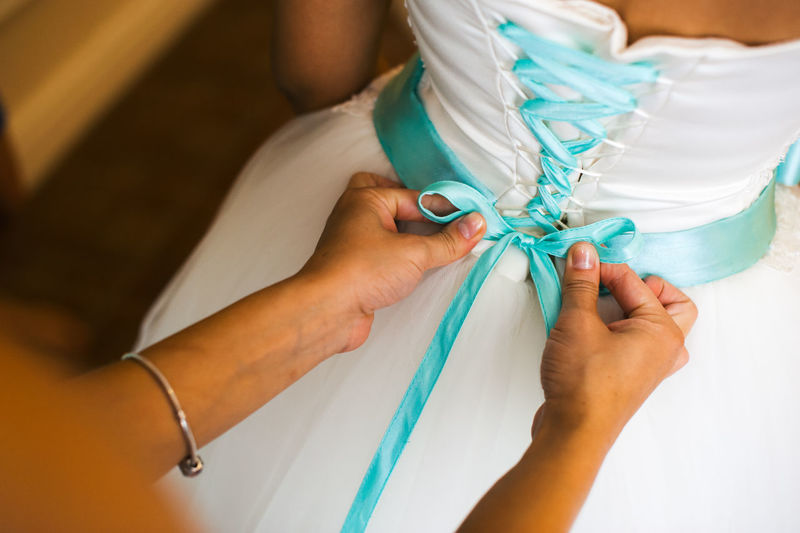 Close-up of woman assisting bride for getting dressed