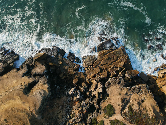 Aerial view of sea waves splashing on rocks