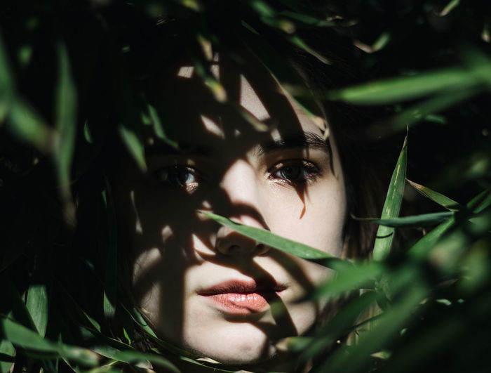 Close-up portrait of young woman amidst leaves