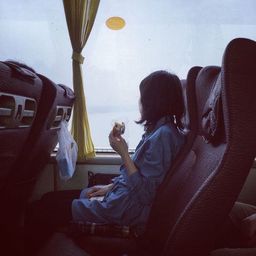 Side view of woman eating food while sitting at bus