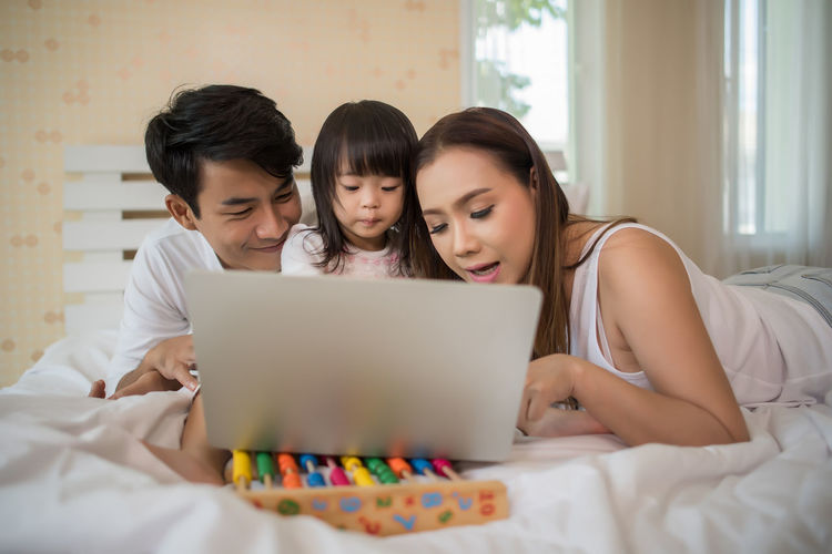 Family using laptop on bed at home