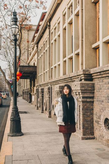 Young woman walking on sidewalk in city
