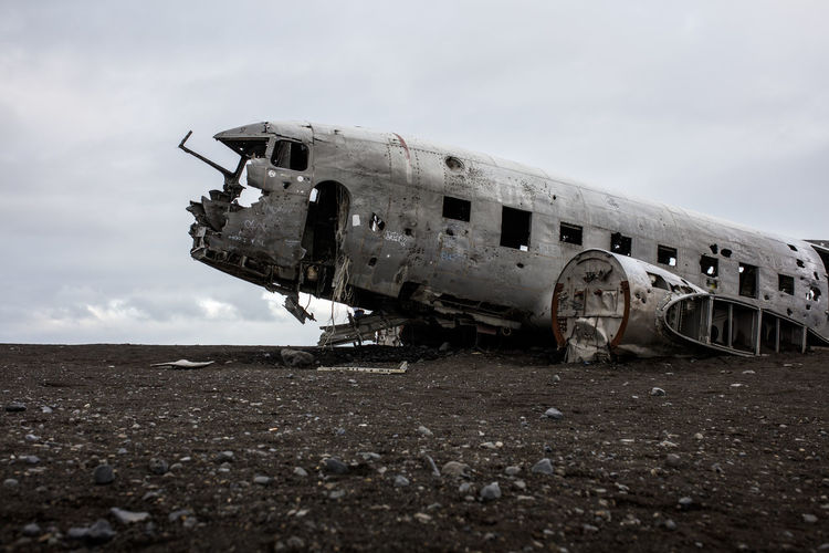 Abandoned airplane on airport runway against sky