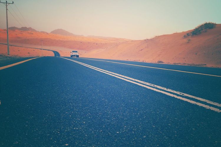 Jeep on road at arabian desert against sky