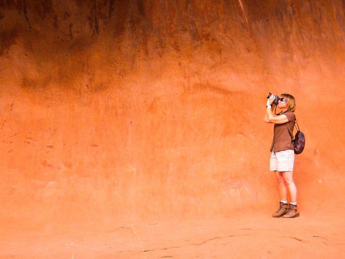 Side view of young woman photographing on mountain