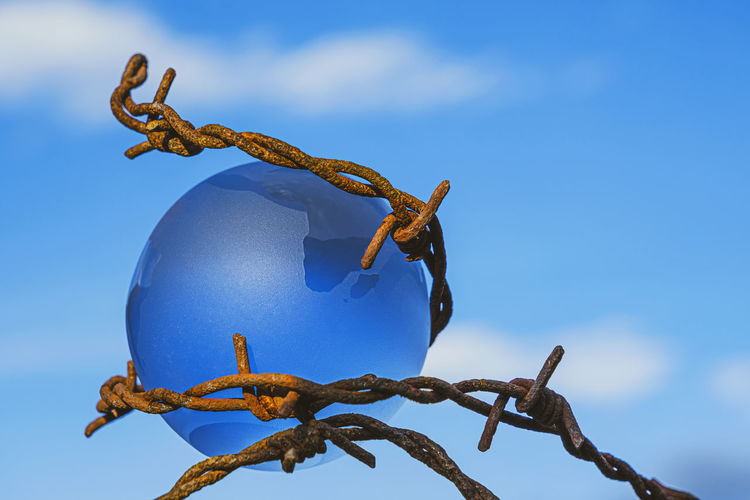 The concept of symbolism. on a blue sky is a glass globe, which is surrounded by rusty barbed wire