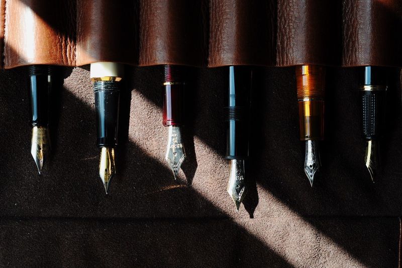 Directly above shot of fountain pens in leather on table