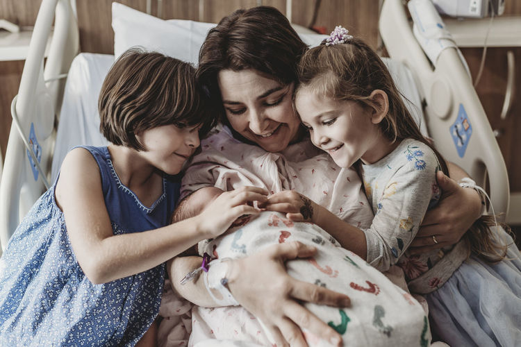 Mid view of mom and daughters holding newborn son