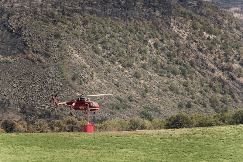 Military helicopter with fire retardant against mountain
