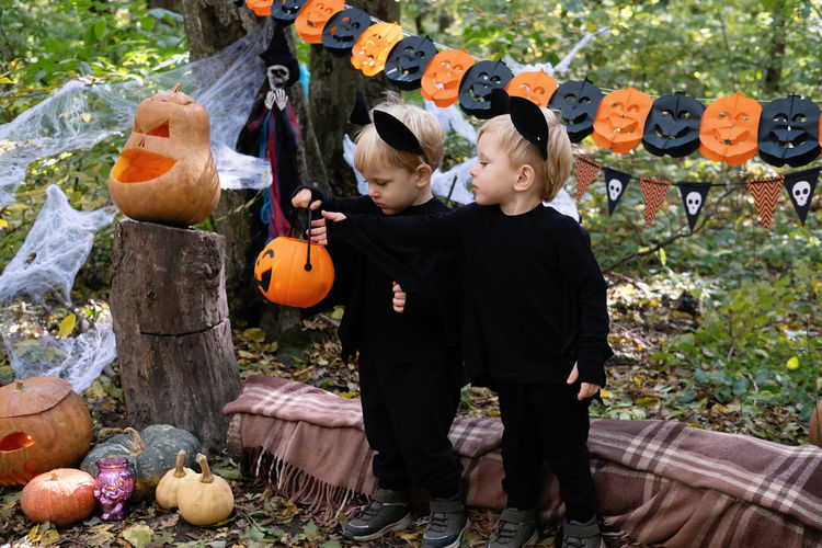 Two happy twins boys kids in halloween costumes having fun in halloween decorations outdoor