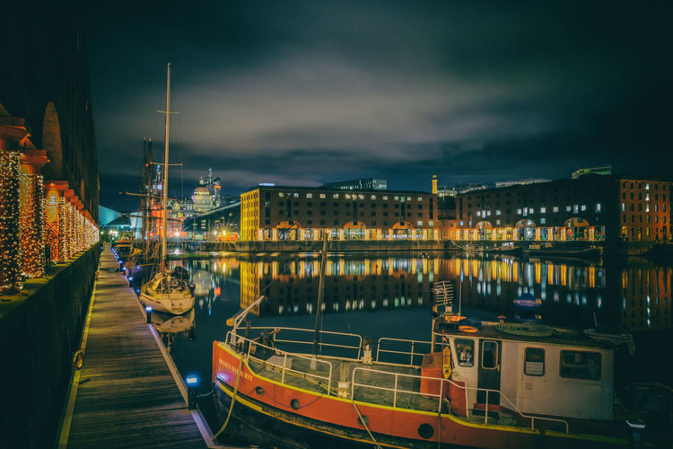 Sailboats moored at harbor against sky at night
