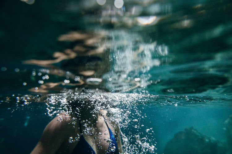 Midsection of woman swimming undersea