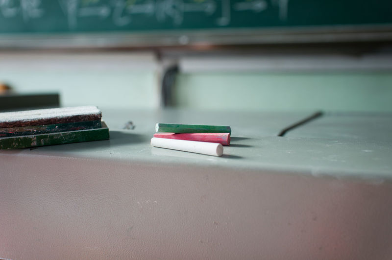 Close-up of chalks and duster on table in classroom