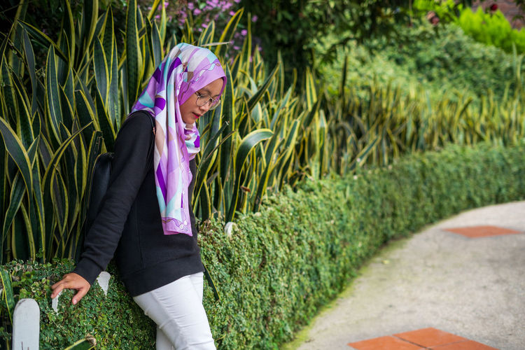 Woman standing on footpath amidst plants