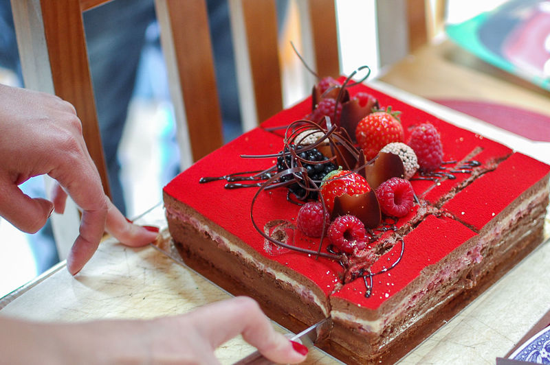 Cropped hands cutting chocolate mousse birthday cake