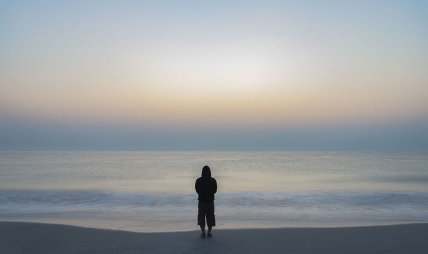 Silhouette of a man looking at the sunrise above the indian ocean. pastel colors