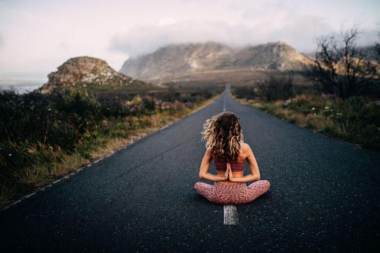 Rear view of woman meditating on road