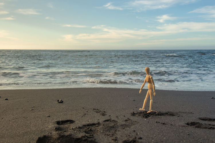 Full length of woman on shore at beach against sky