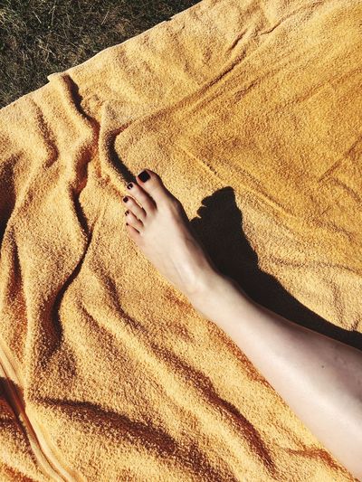Low section of woman relaxing on blanket during sunny day