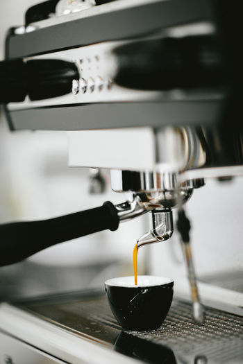 Close-up of cup on espresso maker in cafe