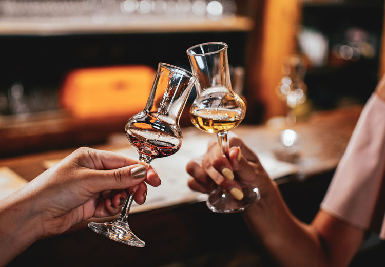 Hands holding brandy glasses in bar. night out, friends, women, lifestyle.