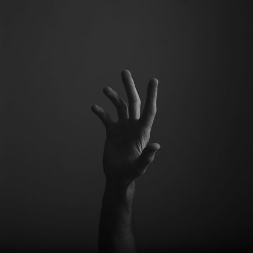 Close-up of human hand gesturing against black background