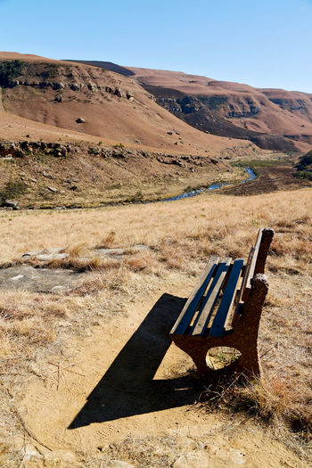 Empty bench on field against sky