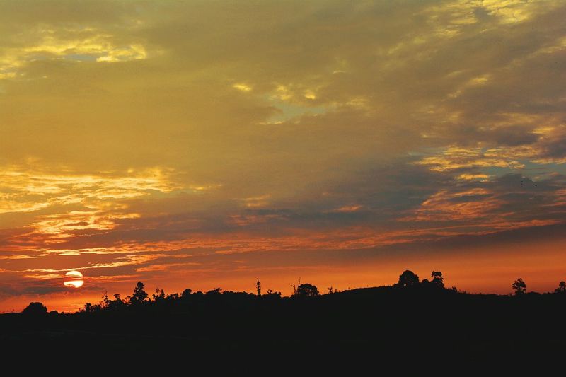 Silhouette landscape against dramatic sky during sunset