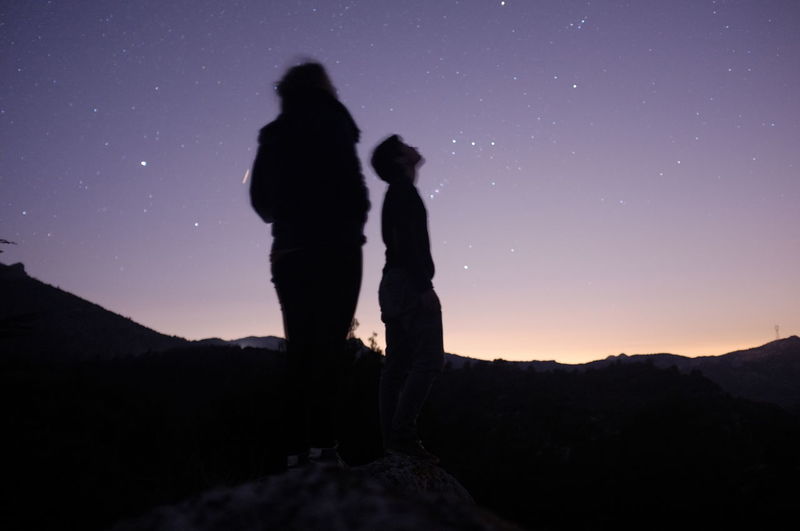 Low angle view of silhouette man and woman looking at stars in sky