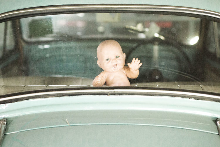 Toy figurine in car seen through rear windshield