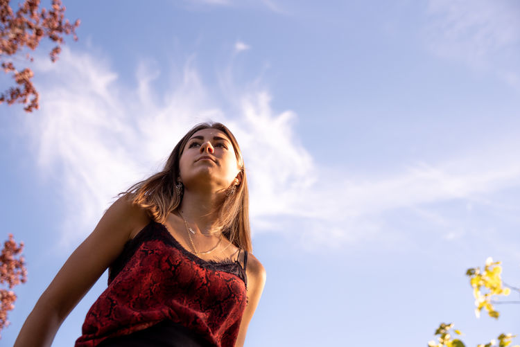 Low angle view of woman looking up against sky