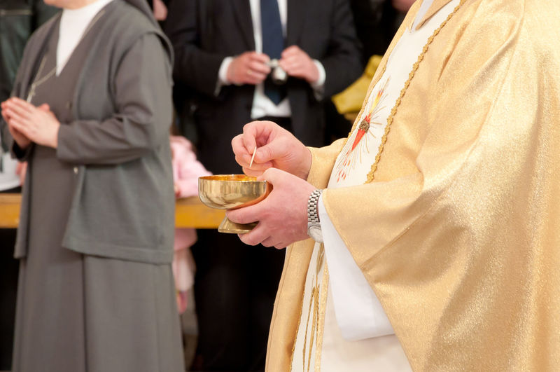 Midsection of priest holding bowl in church