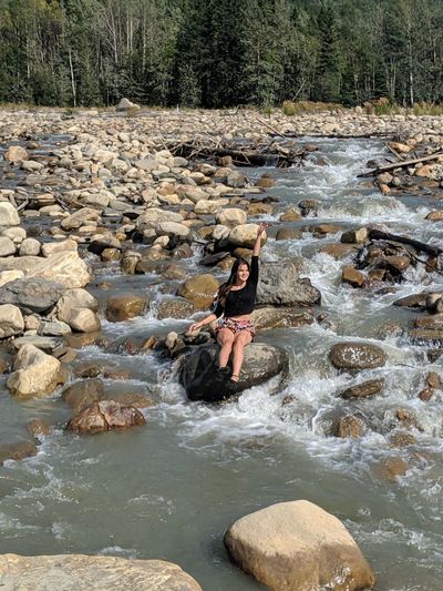 Portrait of woman sitting on rock by river