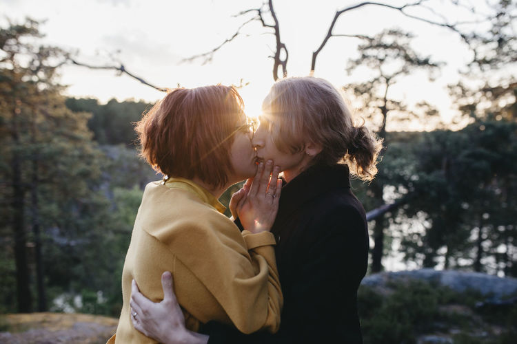 Couple kissing against trees and plants