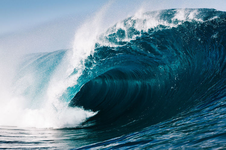 Close-up of sea waves splashing against blue sky