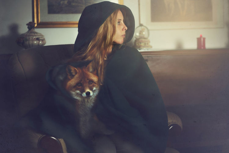 Woman with fox covered with blanket at home
