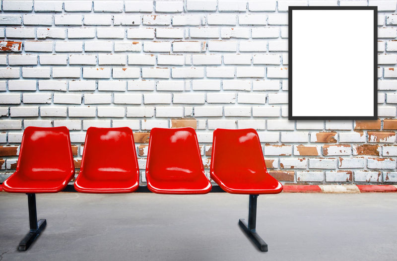 Blank advertising billboard or wide screen television and red chair with old vintage buildings 
