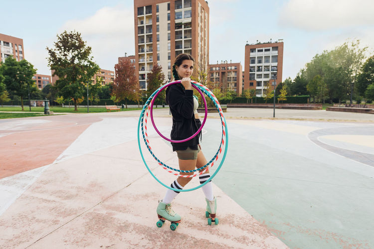 Young woman holding hoops skating at sports court