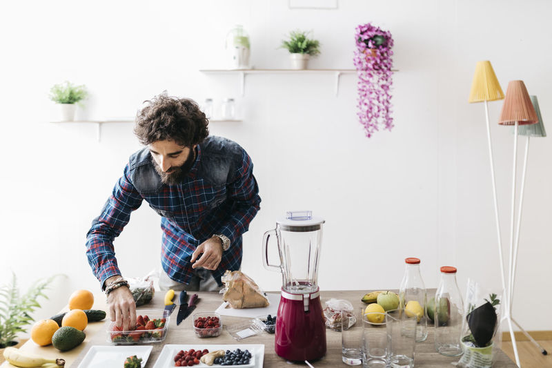 Man preparing smoothies with fresh fruits and vegetables at home